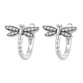 Silver dragonfly-shaped earrings with clear gemstones on a white background
