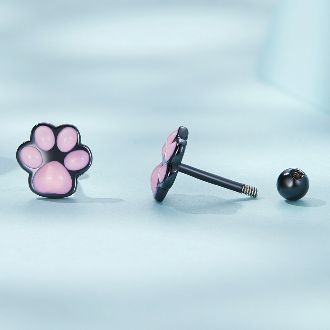 Pair of pink paw print earrings on a white background