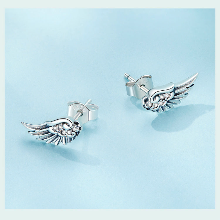 Silver wing-shaped earrings with gemstones on a white background
