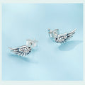 Silver wing-shaped earrings with gemstones on a light blue background