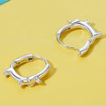 Silver hoop earrings on a yellow background with text about jewelry quality.