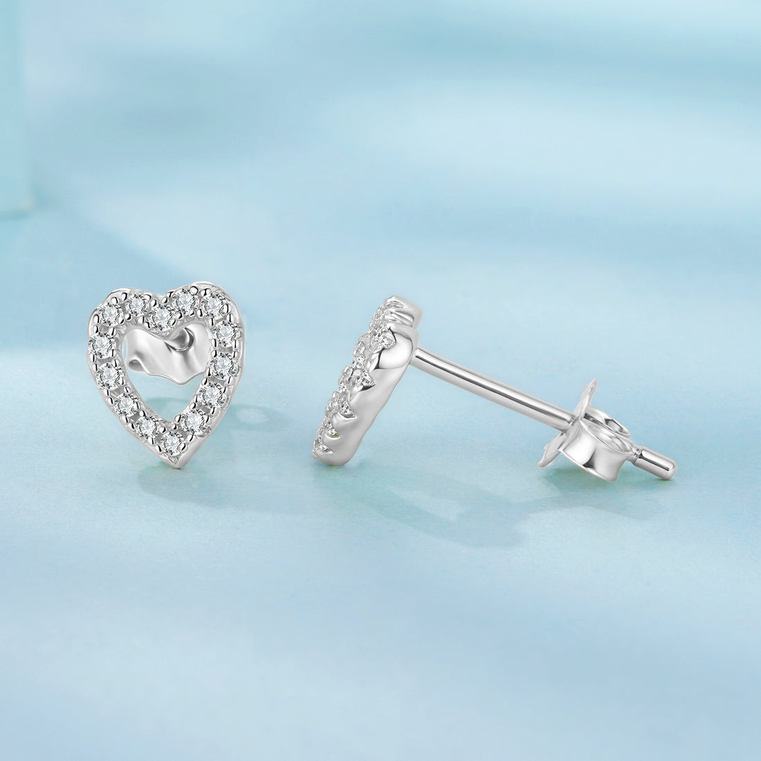 Heart-shaped silver earrings with clear stones on a white background