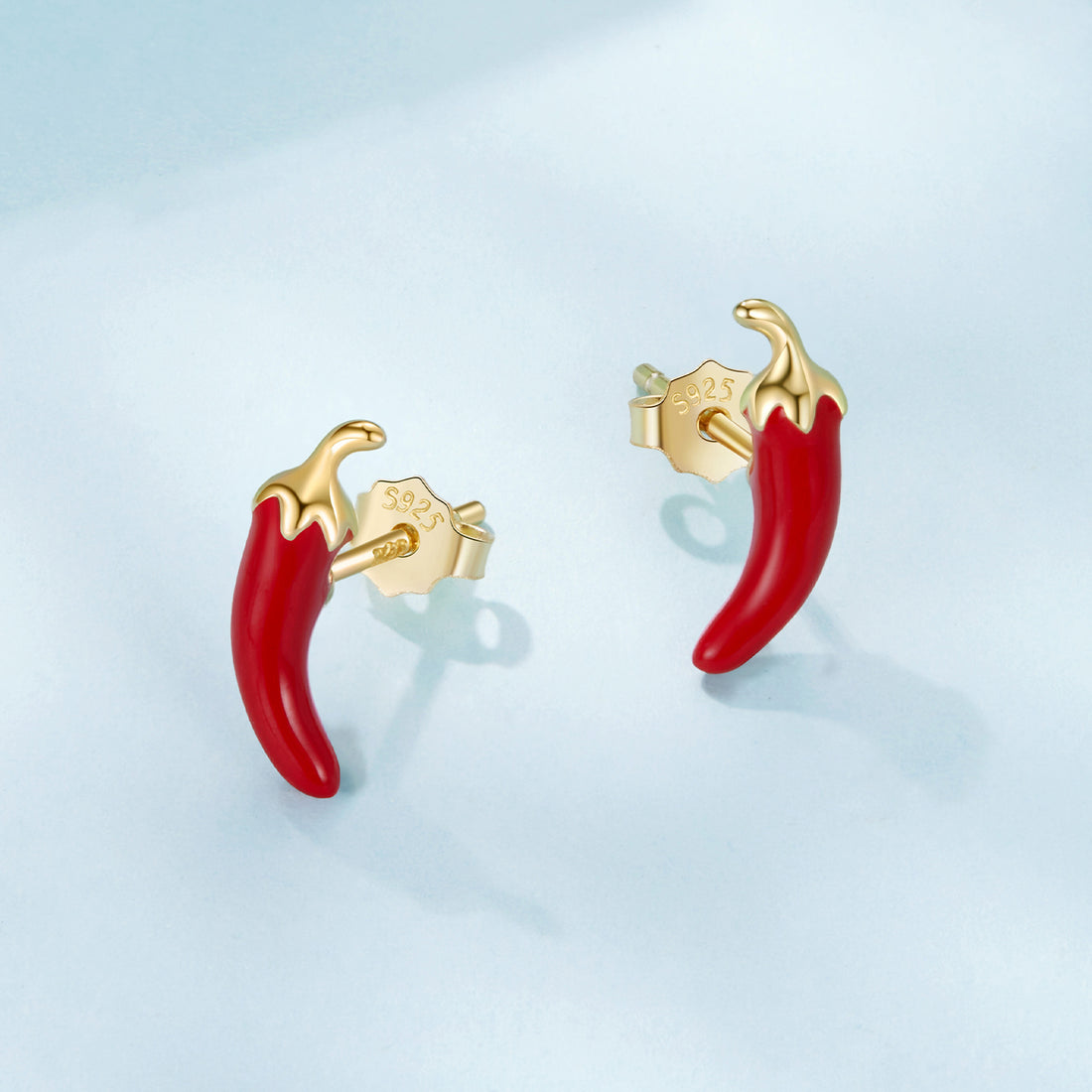 Red chili pepper-shaped earrings with gold posts on a light blue background