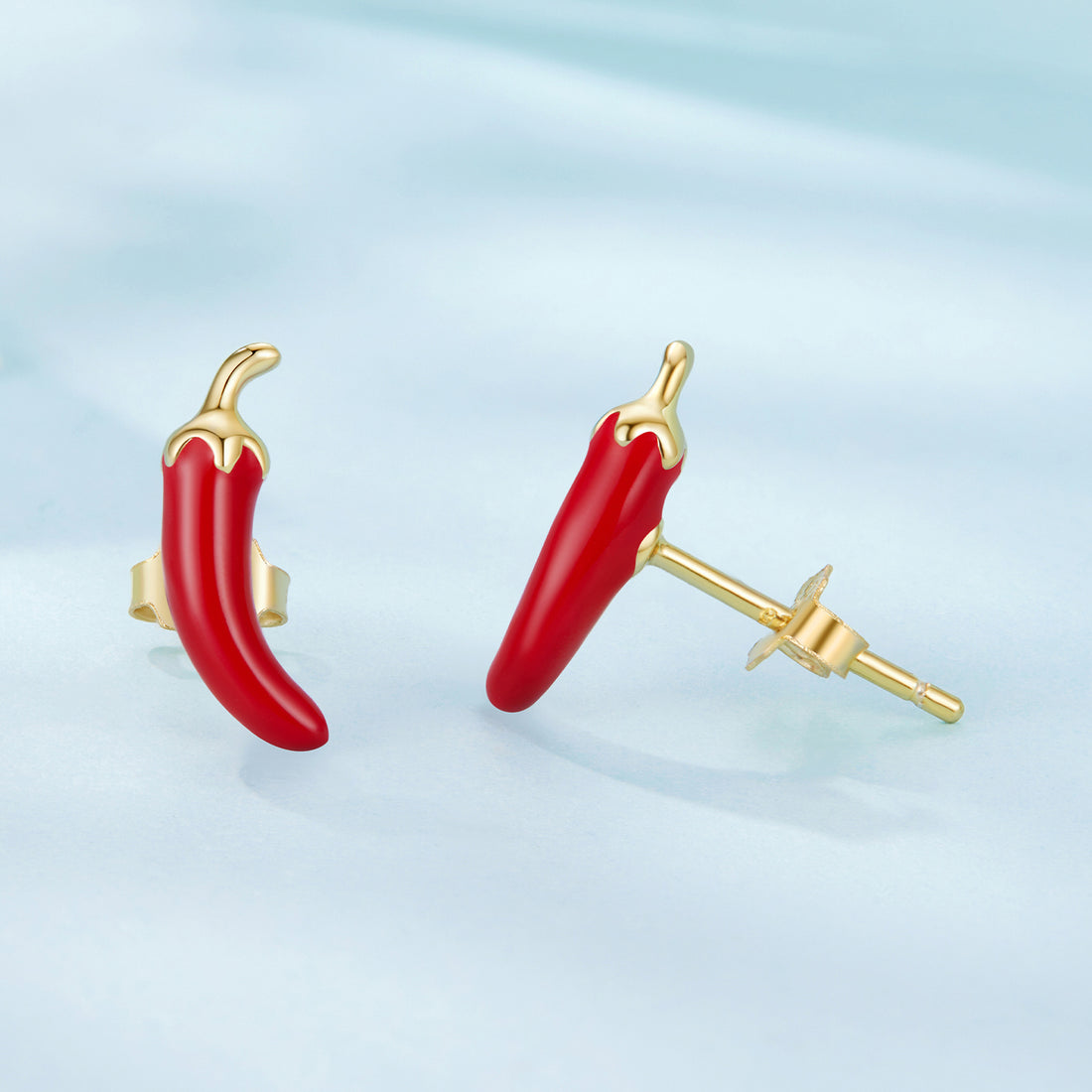 Red chili pepper-shaped earrings with gold posts on a light blue background