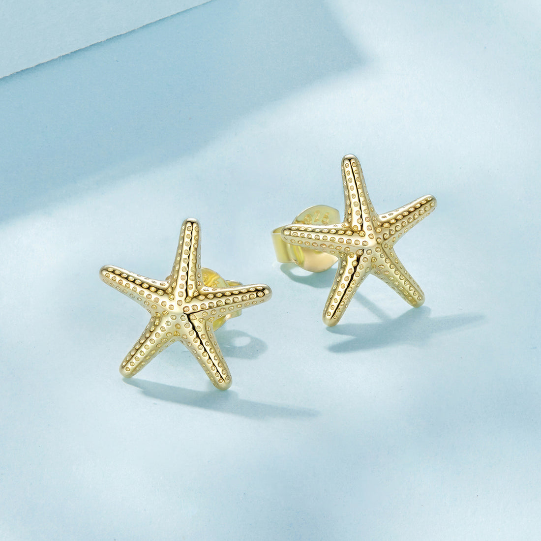 Gold starfish earrings on a white background
