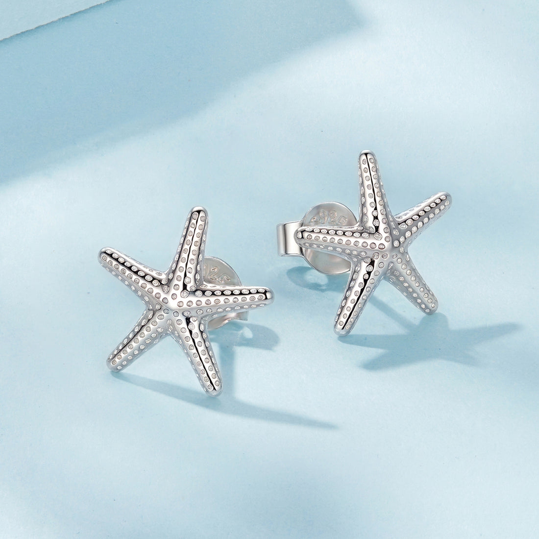 Starfish-shaped silver earrings on a light blue background