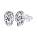 Silver skull earrings with purple gemstones on a white background