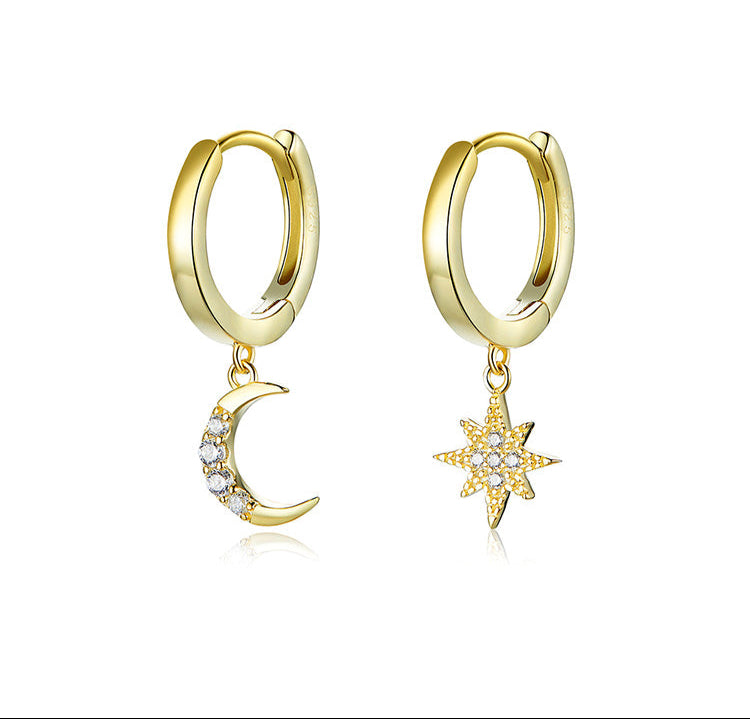 Gold hoop earrings with moon and star charms on a white background