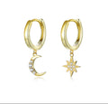 Gold hoop earrings with moon and star charms on a white background