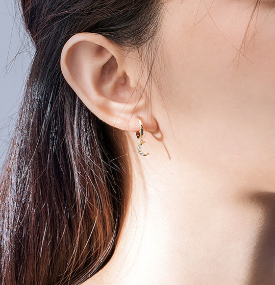 Close-up of a woman wearing a gold earring with a gray background