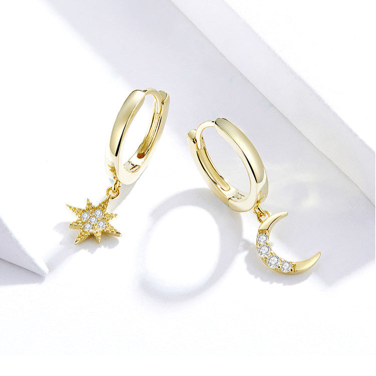 Gold hoop earrings with moon and star charms on a white background