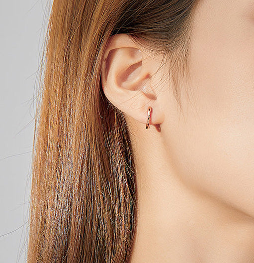 Close-up of a person wearing a gold earring with a gray background