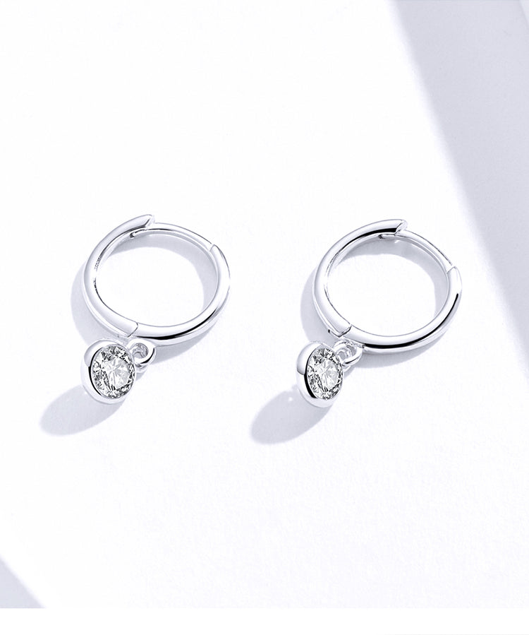 Silver hoop earrings with heart-shaped gemstones on a white background