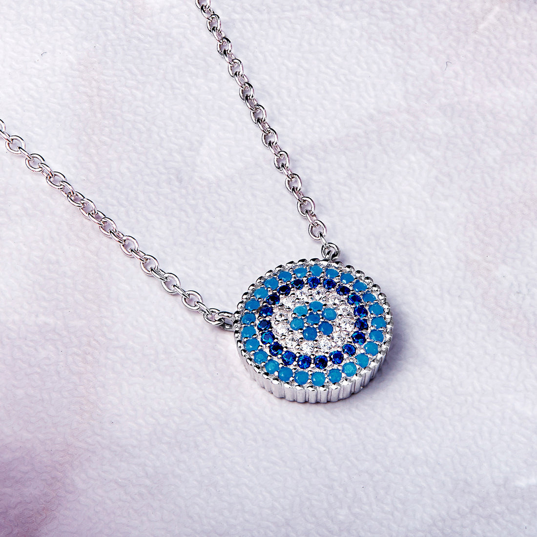 Necklace with a circular pendant featuring blue and white stones on a white background