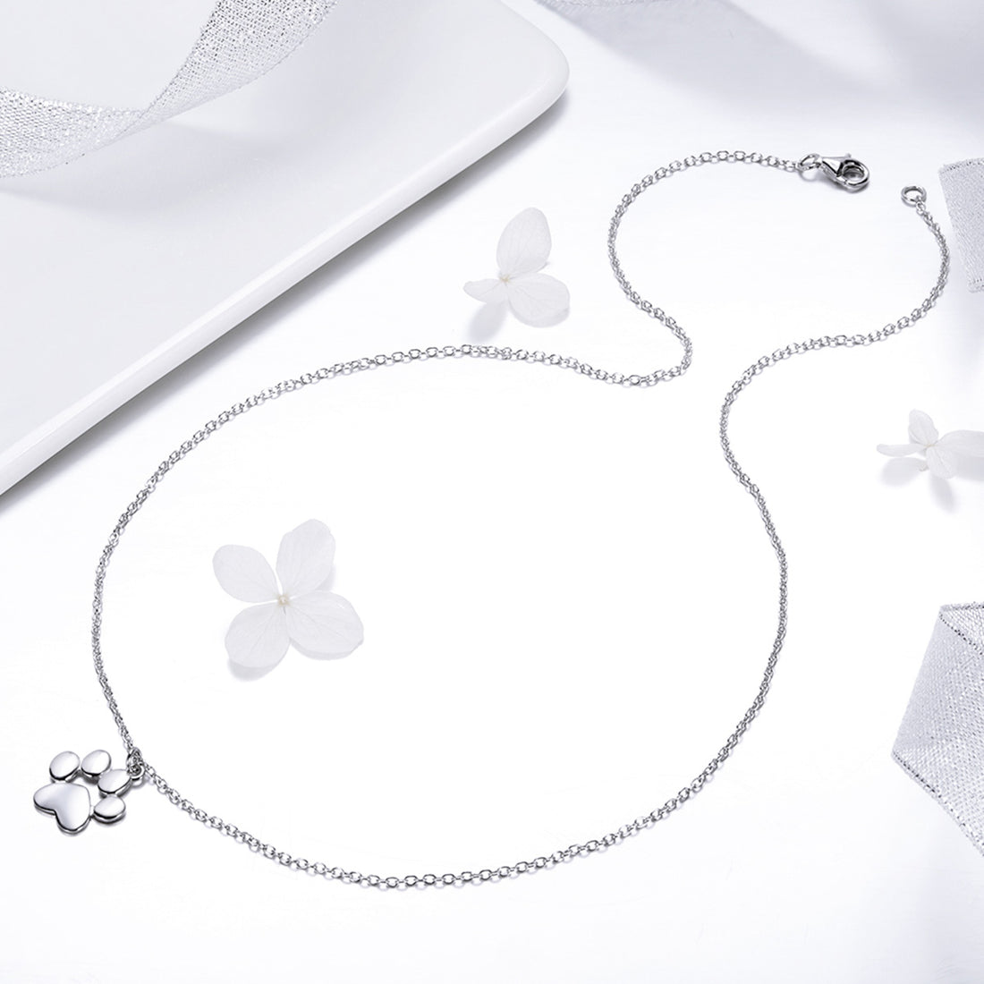 Silver paw print necklace on a white background