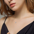 Woman wearing a black dress with a necklace against a neutral background