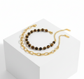 Gold chain necklace with black beads on a white background
