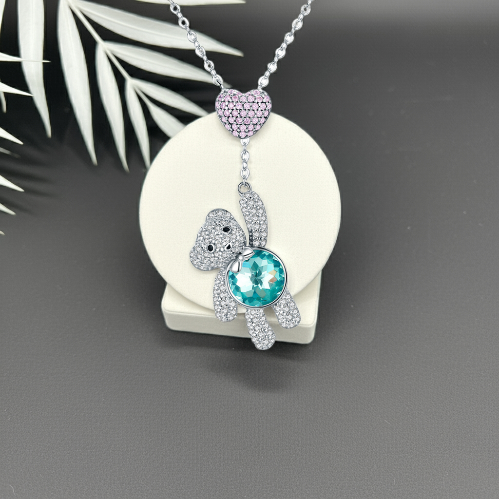 Necklace with a teddy bear pendant featuring a blue gemstone on a white background